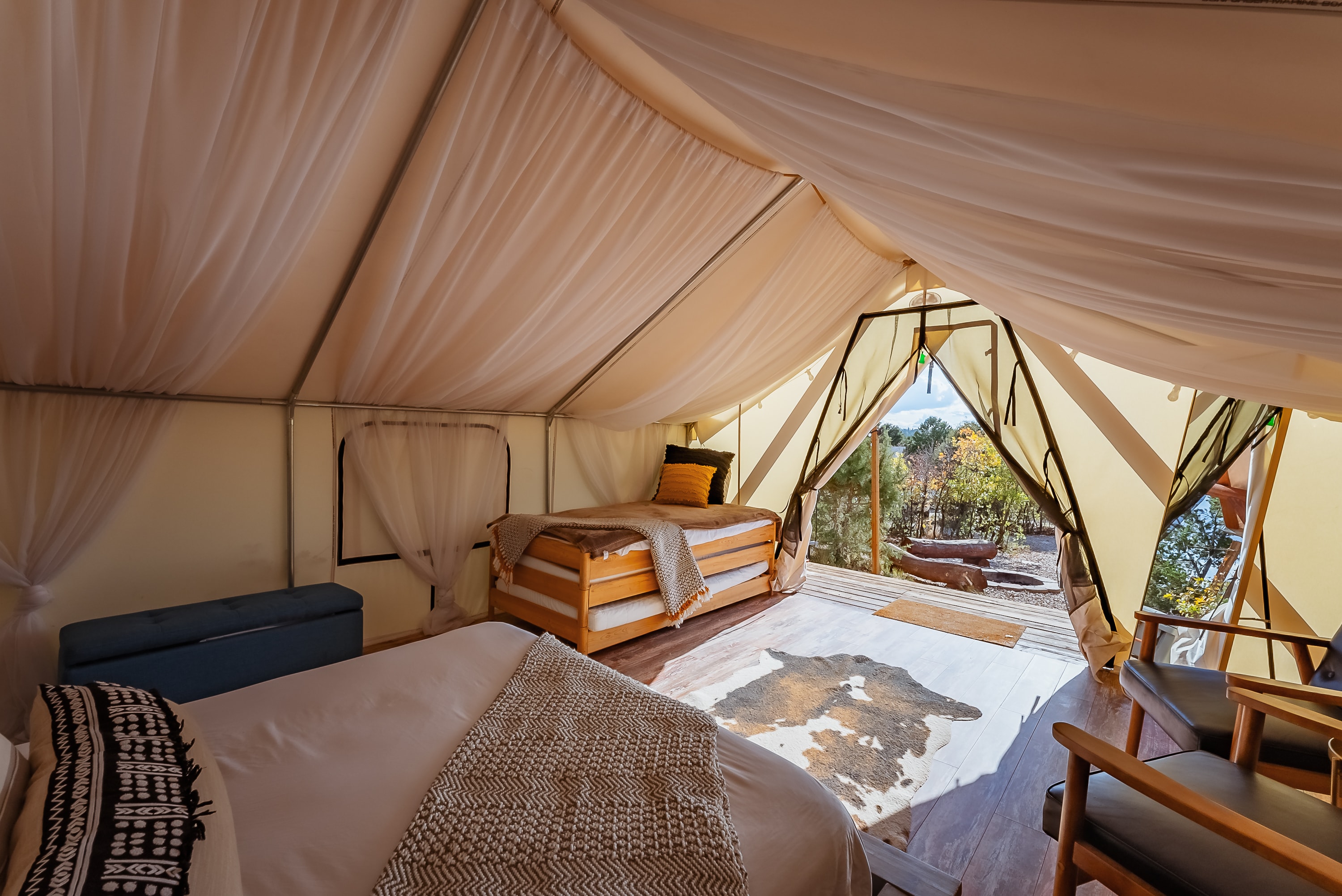 Luxurious glamping tent interior with two beds and a scenic view.